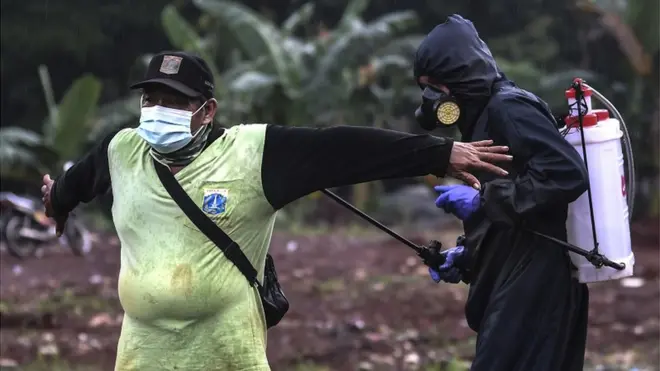 Selesai bertugas, para penggali kubur disemprot cairan disinfektan.