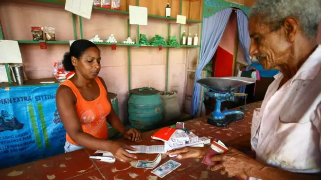 Una mujer en Cuba vende productos a un hombre mayor que le devuelve billetes, en la ciudad de Trinidad.