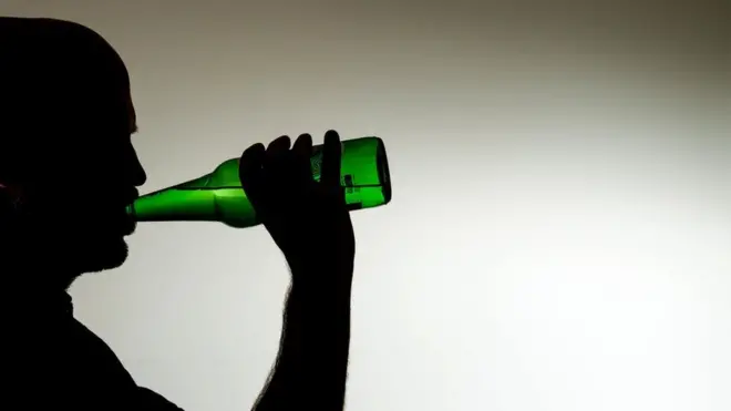 man wey dey drink beer from bottle