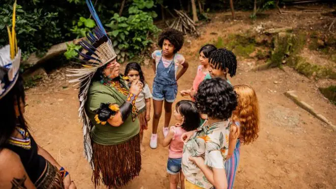 Mulher indígena conversa com grupo de crianças