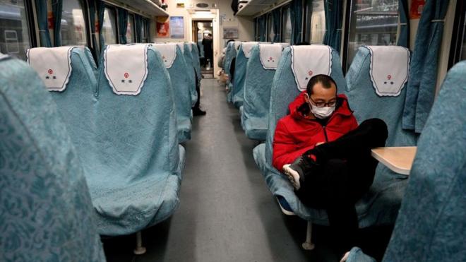 A passenger wearing a face mask uses his phone as he sits inside a train at Nanjing railway station in Nanjing, the capital of Chinas eastern Jiangsu province on March 13, 2020. - China reported just eight cases of the covid-19 coronavirus outbreak on March 13, with no new domestic infections outside the epicentre of Hubei province. (Photo by Noel Celis / AFP) (Photo by NOEL CELIS/AFP via Getty Images)