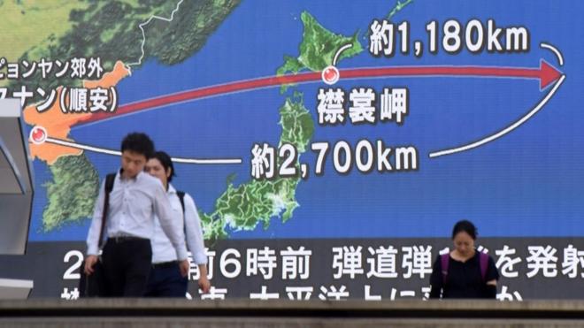 在東京街頭，行人走過展示有日本和朝鮮半島地圖的巨大屏幕。