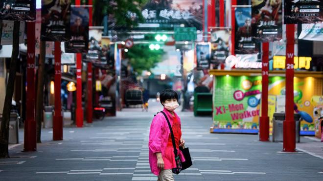 2021/05/21: A woman wearing a facemask as a precaution against the spread of covid-19 walks along an empty street in the shopping district, Ximending, during the covid-19 outbreak