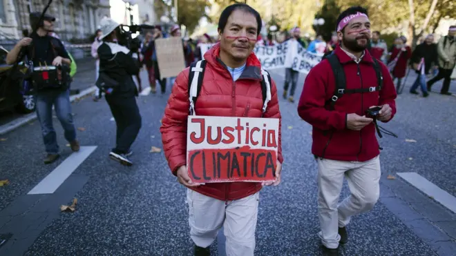 Saul lors d'une manifestation, tenant une pancarte indiquant "Justice pour le climat".