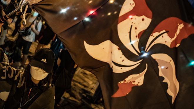 香港九龙荔枝角惩教所（收押所）外一群“反送中”示威者举起经改编的“流血”香港区旗（3/6/2020）