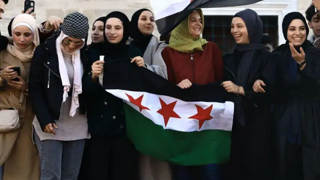 8 Kasım'daki yönetim değişikliğinin ardından İstanbul Fatih'teki kutlamalara katılan Suriyeli kadın bayrak taşıyor