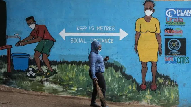 Une femme avec un masque facial passe devant des graffitis qui favorisent la distanciation sociale, pour freiner la propagation du coronavirus COVID-19, à Kibera, Nairobi, le 15 juillet 2020.