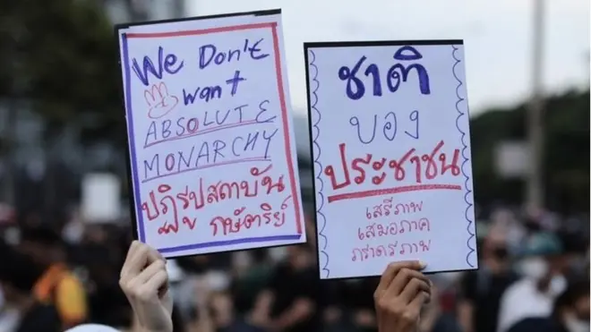 ผู้ชุมนุมกลุ่ม "ราษฎร" ถือป้ายระบุข้อเรียกร้องระหว่างเดินขบวนจากแยกสามย่านไปสถานทูตเยอรมนีเมื่อวันที่ 26 ต.ค.