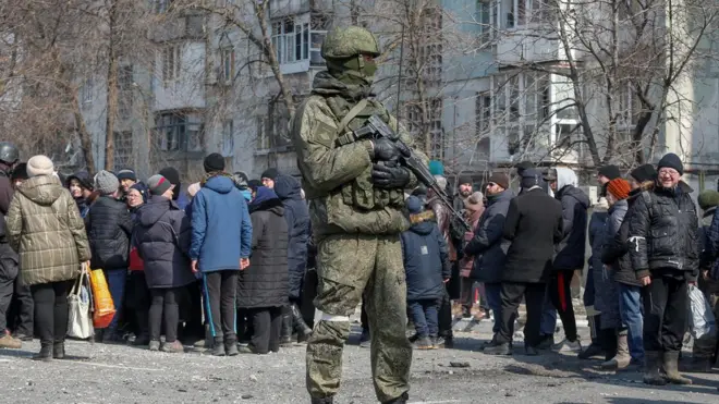 Российский солдат на фоне мирных жителей Маруиполя