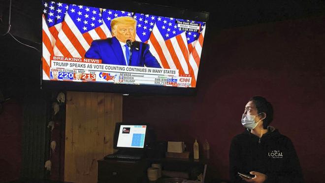 北京酒吧裏的一名女服務員正在觀看美國大選直播。