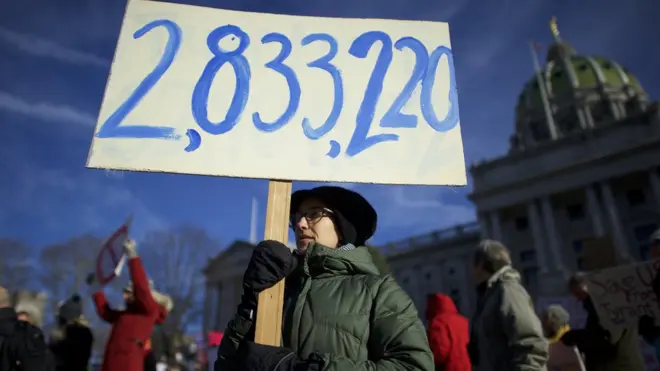 Hillary Clinton'ın Trump'tan fazla aldığı oyların sayısını döviz haline getirmiş bir protestocu.