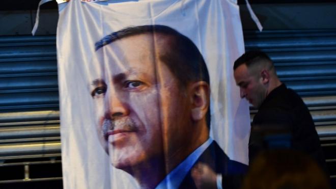 Un hombre camina frente a un banner con el rostro de Erdogan.