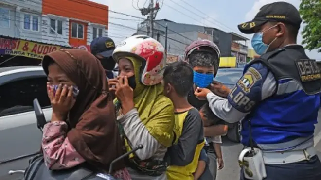 Petugas Dinas Perhubungan memasangkan masker kepada warga yang melanggar Perda Wajib Memakai Masker di Tempat Umum di Pasar Kepandean, Serang, Banten, Kamis (27/8/2020).