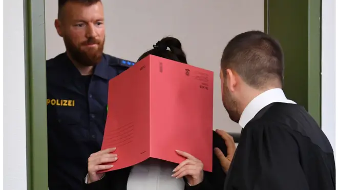 جنيفر و. أثناء دخولها المحكمة وقد حجبت وجهها بملف كبير