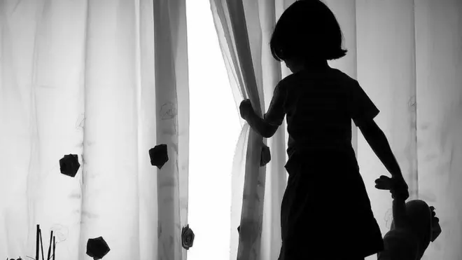 small girl wey dey look outside from window