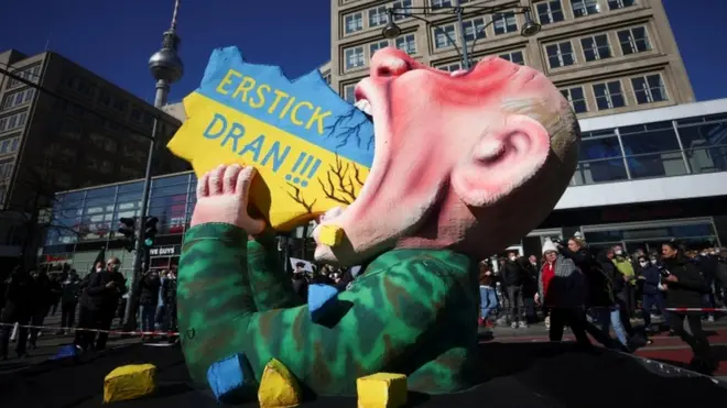 Робота дюссельдорфського художника Жака Тіллі із зображенням Путіна та написом "Вдавися!!!" на антивоєнній демонстрації "Зупиніть війну. Мир і солідарність для народу в Україні" в Берліні, Німеччина, 13 березня 2022 року