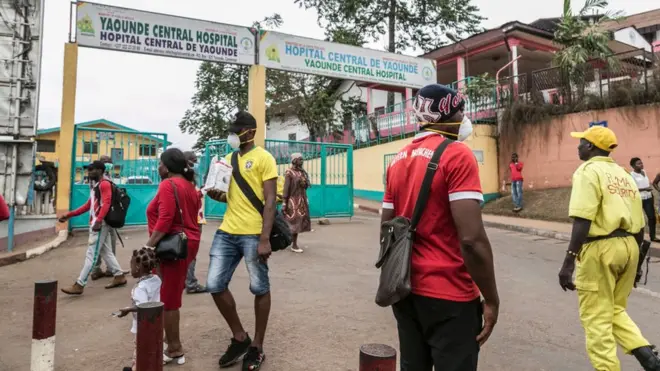 Some people wear masks as they walk by the entrance to the Yaounde General Hospital in Yaounde
