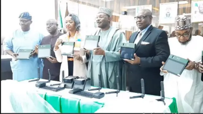 INEC Chairman Prof. Mahmud Yakubu wit oda senior members holding the new voters registration device