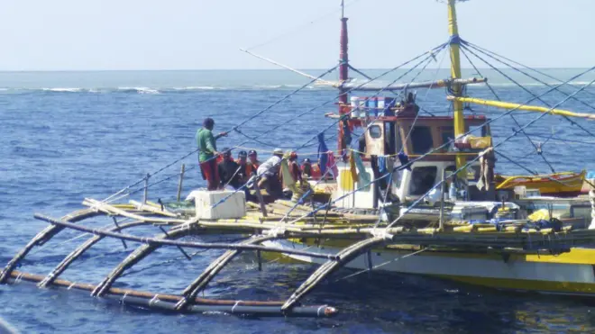 Aparat penjaga pantai Cina (bertopi hitam dan jaket oranye) mendekati kapal nelayan Filipina di Scarborough Shoal di Laut Cina Selatan dalam satu insiden tahun 2015.