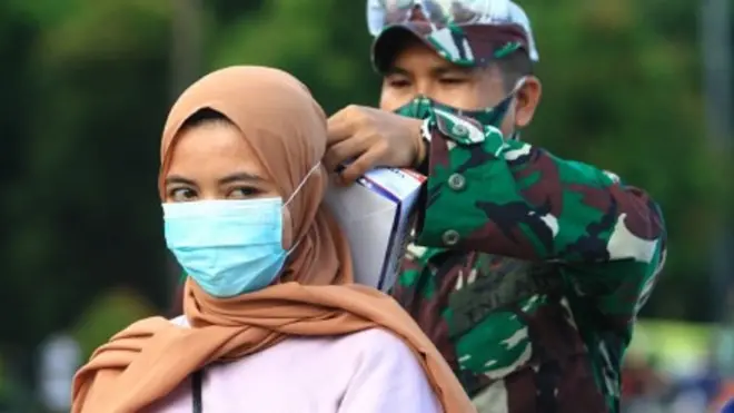 Seorang personel TNI AD memasangkan masker kepada warga yang terjaring razia kepatuhan penggunaan masker di Taman Digulis, Pontianak, Kalimantan Barat, Minggu (12/7/2020). Dinas Kesehatan Kalbar bersama TNI dan Satpol PP gencar melakukan sosialisasi protokol kesehatan.