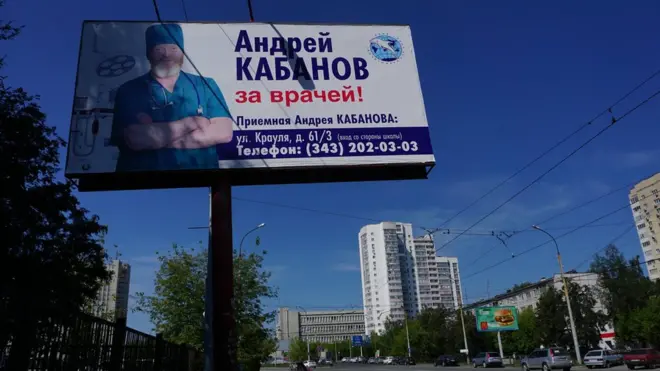 На плакатах Андрей Кабанов одинаково уверенно выглядит в костюме врача...