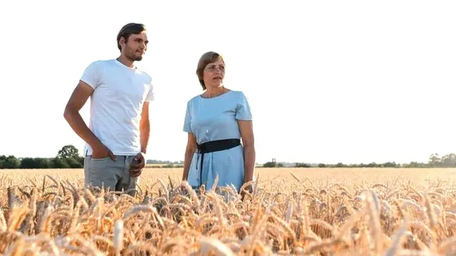 Nadiya and her son Dmytro standing in one of their wheat fields.