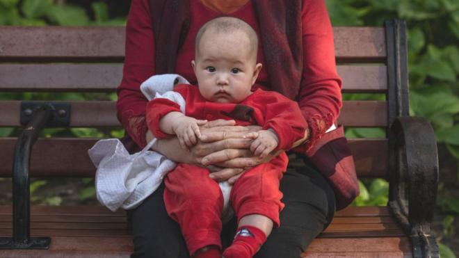 北京一名婦女在公園抱著一個嬰兒（2021年5月12日）