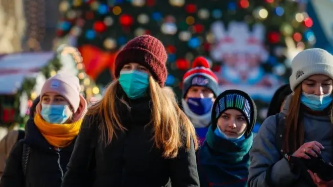 Russian people wearing a protective face masks walk on a street decorated for the upcoming Christmas and New Year"s celebrations during the pandemic of SARS-CoV-2 coronavirus Moscow, Russia, 28 December 2020