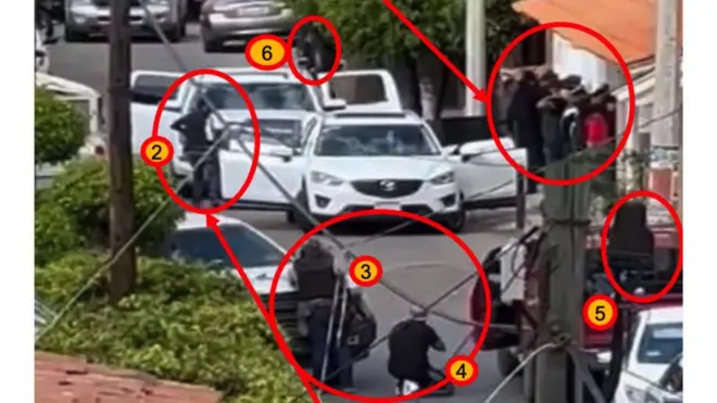 En la imagen se observa a la derecha a un grupo de personas con las manos en alto antes de que se inicie una ráfaga de disparos en su contra.