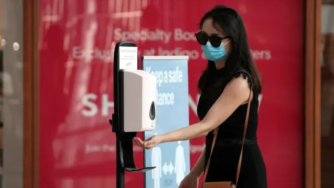 A woman wearing a face mask sanitizes her hand at Yorkdale Shopping Centre on July 7, 2020 in Toronto, Canada.