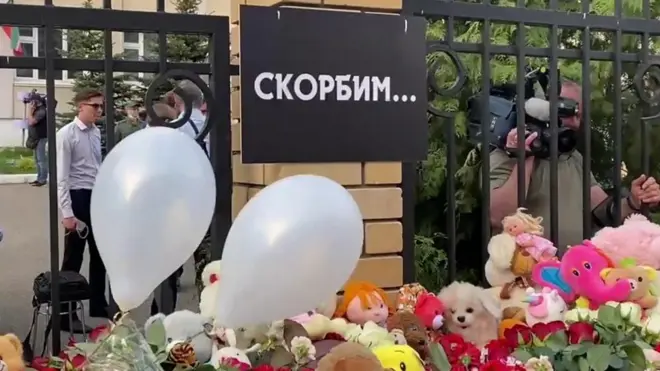 Школьники и родители несут цветы и игрушки к школе, где была стрельба