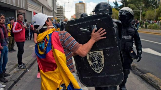 Un manifestante se enfrenta a un policía antimotines en Ecuador