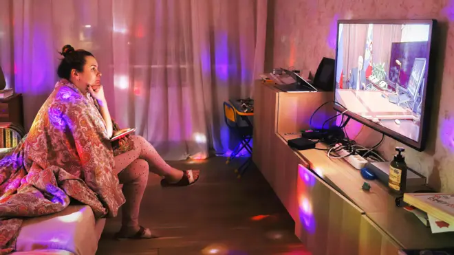 ผู้หญิงชาวเมืองเซนต์ปีเตอร์สเบิร์กนั่งชมการรายงานข่าวเกี่ยวกับประธานาธิบดีปูตินทางโทรทัศน์เมื่อสัปดาห์ที่แล้ว