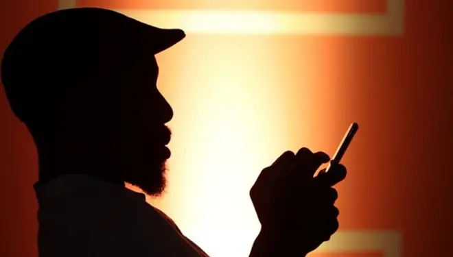 ภาพเค้าโครงคนใส่หมวกนั่งหันข้าง มือคีบมวนบุหรี่