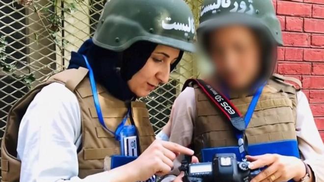Wahida and a colleague wearing a helmet looking at a camera
