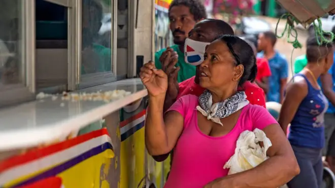 mujer espera por comida en república dominicana