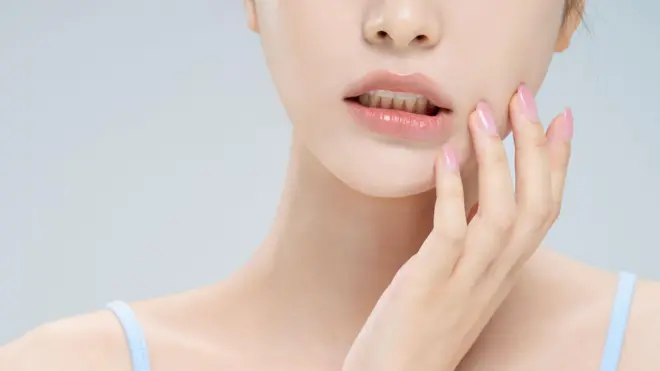 Elini yüzüne götürmüş ve ağzını hafif aralamış bir kadın 