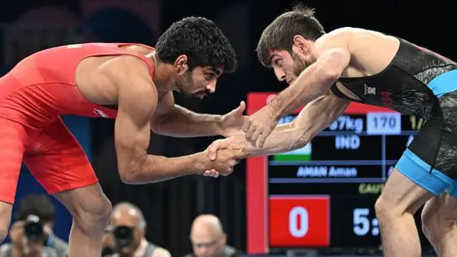 India's Aman Aman (red) wrestles Albania's Zelimkhan Abakarov (blue) in their men's freestyle 57kg wrestling quarter-final match