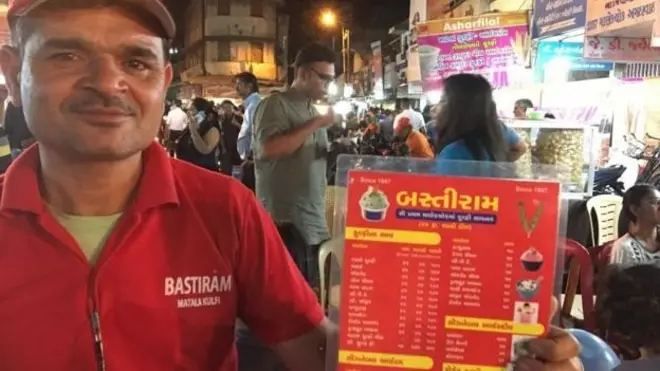 ایک ریستوراں کا ملازم اپنا مینوکارڈ دکھا رہا ہے