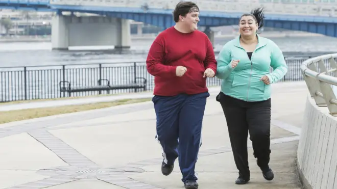 Полные девушка и молодой человек на пробежке в городе