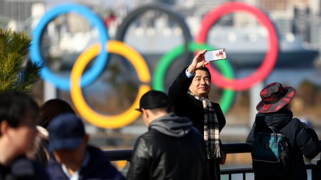 Members of the public get pictures near the Olympic rings on Tokyo