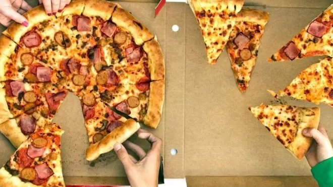 Unas personas tomando pedazos de una pizza