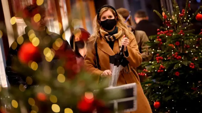 Mujer con mascarilla entre árboles de Navidad
