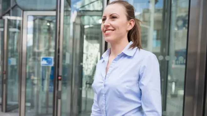 Una joven con expresión orgullosa. Al fondo, una puerta giratoria