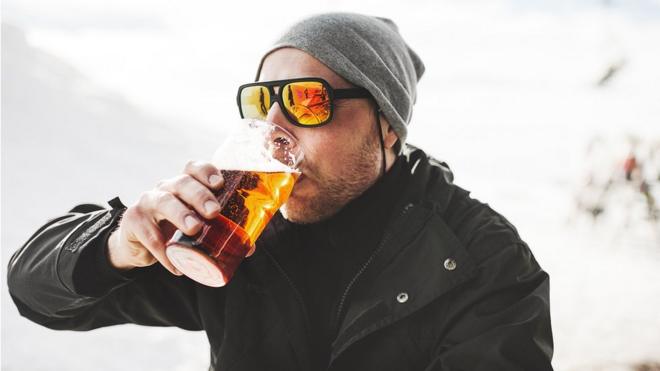 Hombre bebiendo cerveza en la nieve