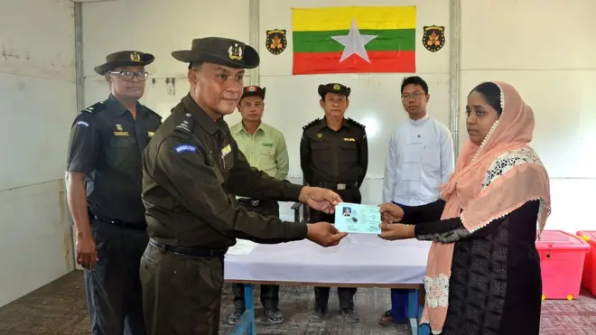 Pejabat imigrasi menyerahkan kartu tanda pengenal kepada seorang Rohingya di kamp Taungpyoletwei, Rakhine.