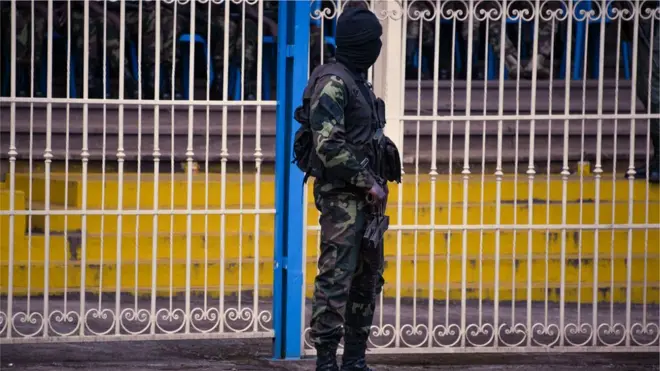 One Rapid Intervention Battalion soldier stand dey watch as dem do burial for soldiers wey die for fight-fight wey happen for Bamenda, Cameroon