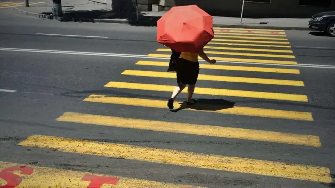Woman with umbrella using a street crossing in Yerevan, Armenia