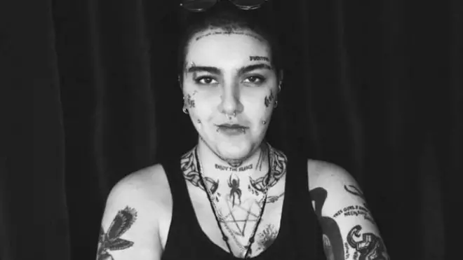 Ribell wọ aṣọ kolapa pẹlu tatoo lara.