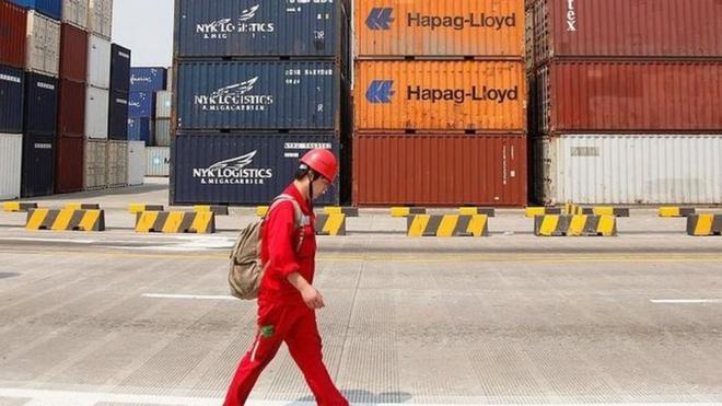 A worker walks past stacked containers at the Yangshan Deepwater Container Port in Shanghai, China on 02 June 2011.